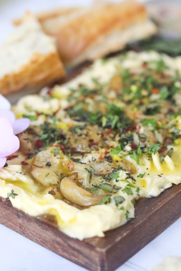 an omelet with mushrooms and herbs sits on a wooden board next to bread