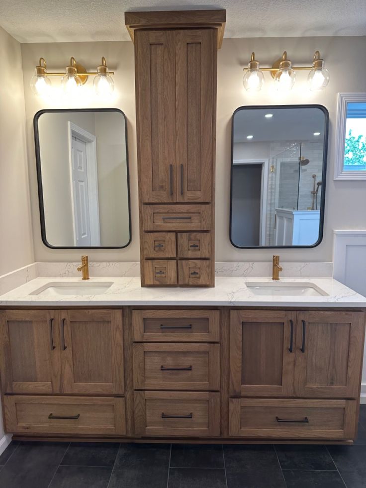 a bathroom with double sinks and two large mirrors on the wall next to each other