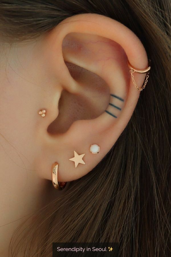 an ear with three different piercings on top of it and two stars in the middle