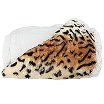 a stuffed animal laying on top of a white blanket with black spots and brown fur