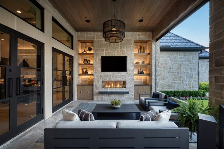 an outdoor living area with couches, tables and television on the wall above it