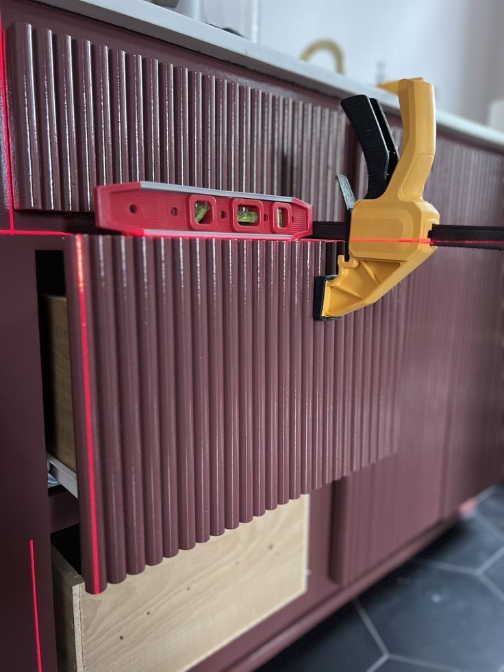 a close up of a cabinet with a tool attached to the door and some drawers