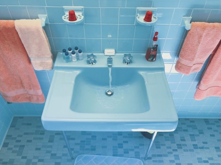 a bathroom with blue tiles and pink towels