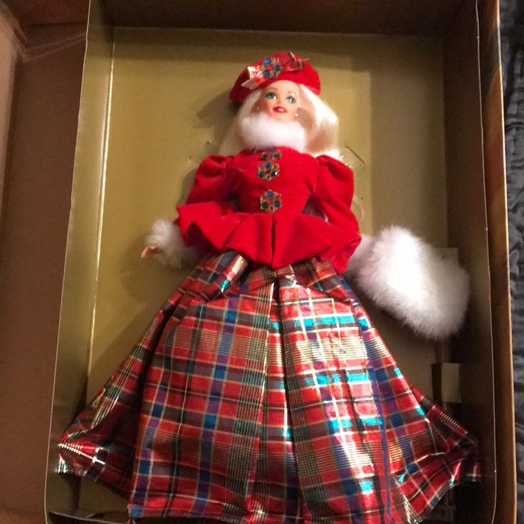 a christmas doll in a cardboard box with plaid dress and fur trimmings on it