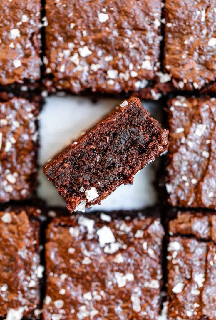 a chocolate brownie with white sprinkles on it is being held up by a fork