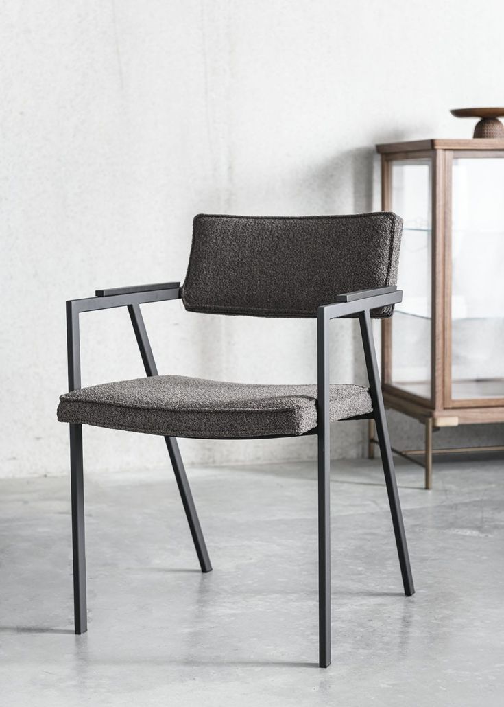 a gray chair sitting in front of a glass case on top of a cement floor