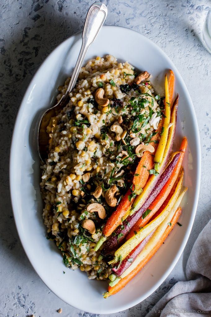 a white bowl filled with rice, carrots and other vegetables next to a spoon