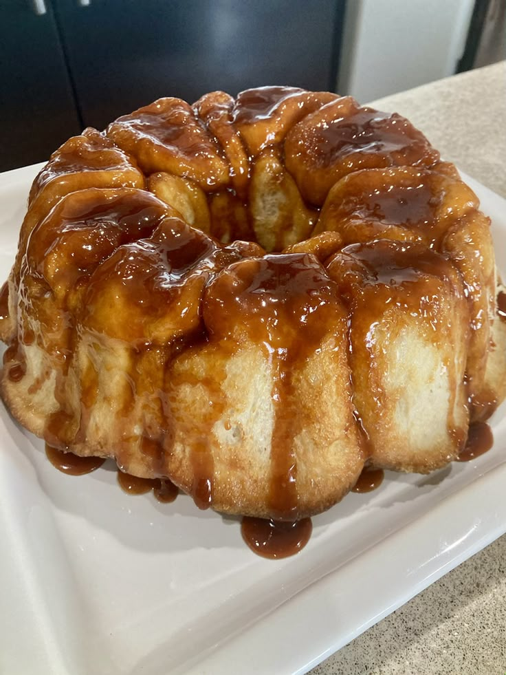 a bundt cake covered in caramel drizzle on a white square plate