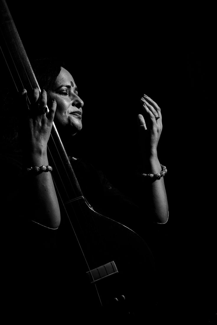 a black and white photo of a woman holding a bass in her right hand while looking up at the sky