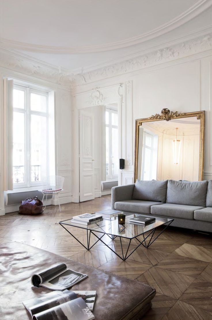 a living room filled with furniture and a large mirror in the middle of it's wall