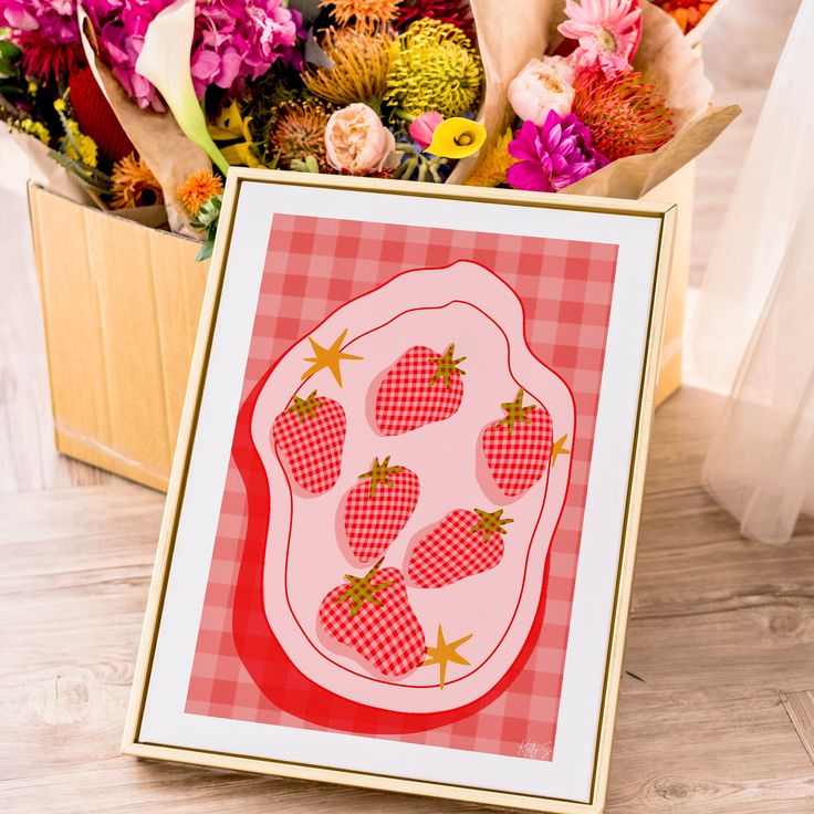 a card with strawberries on it sitting in front of flowers and a box of cards