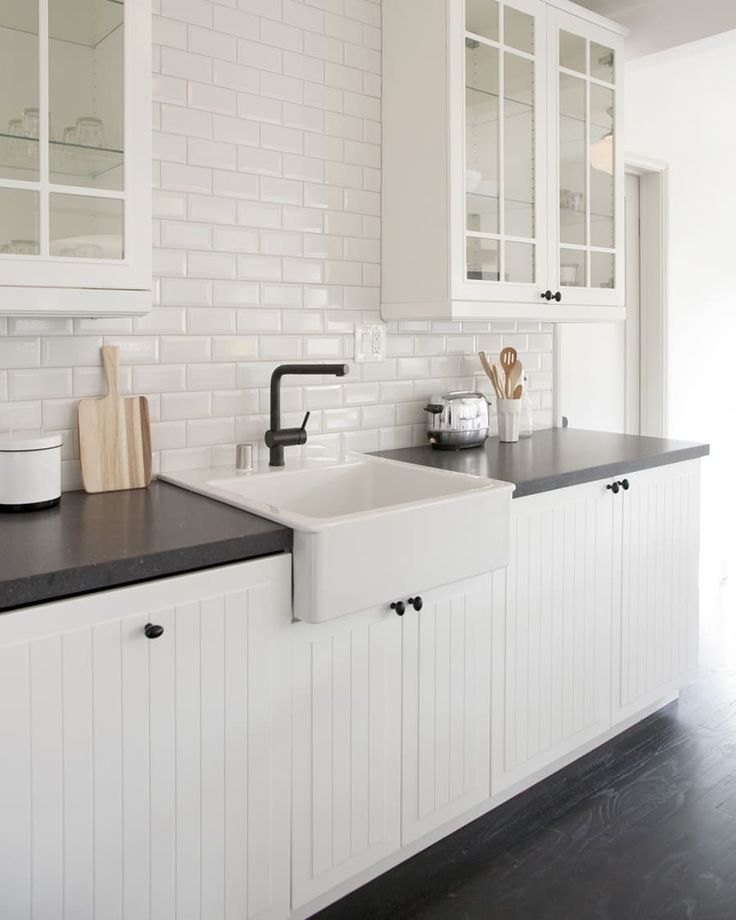 a kitchen with white cabinets and black counter tops