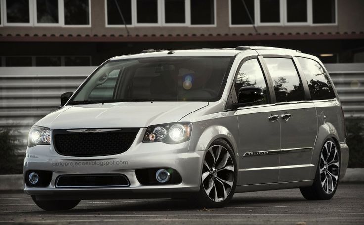 a white minivan parked in front of a building with black rims on it