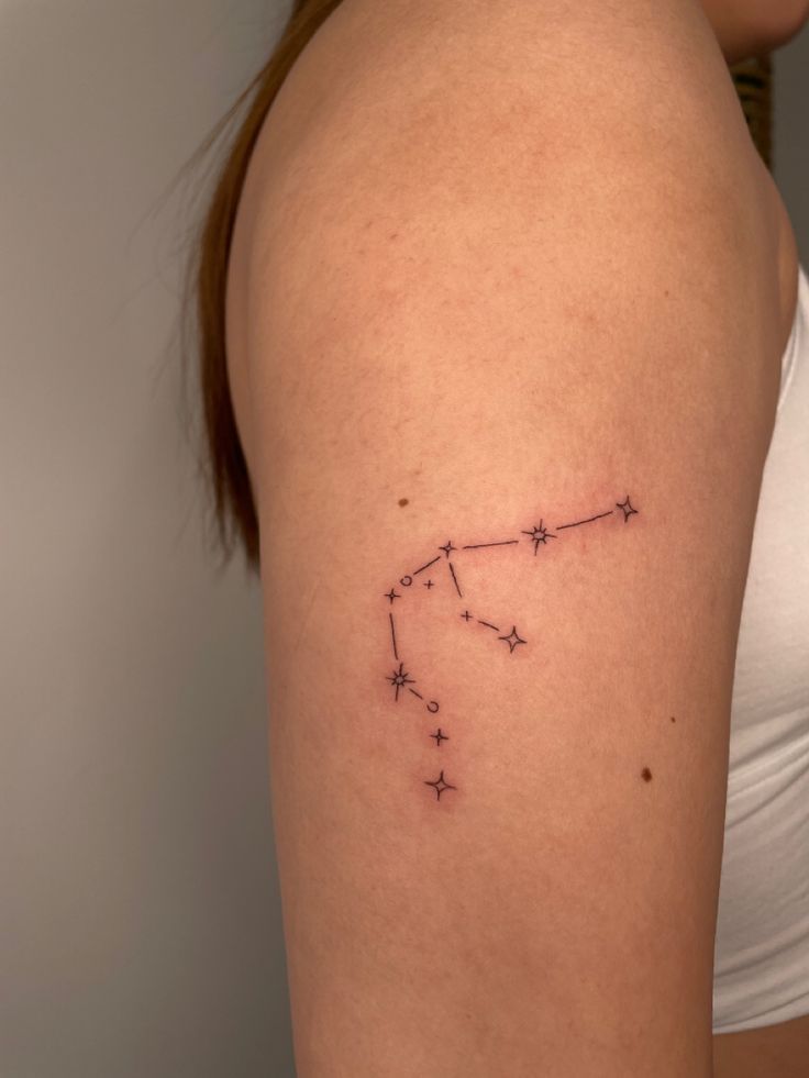 a woman's upper arm with a small star tattoo on the left side of her shoulder