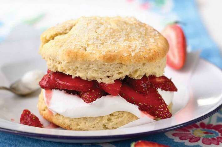 a biscuit sandwich with strawberries and whipped cream on it is sitting on a plate