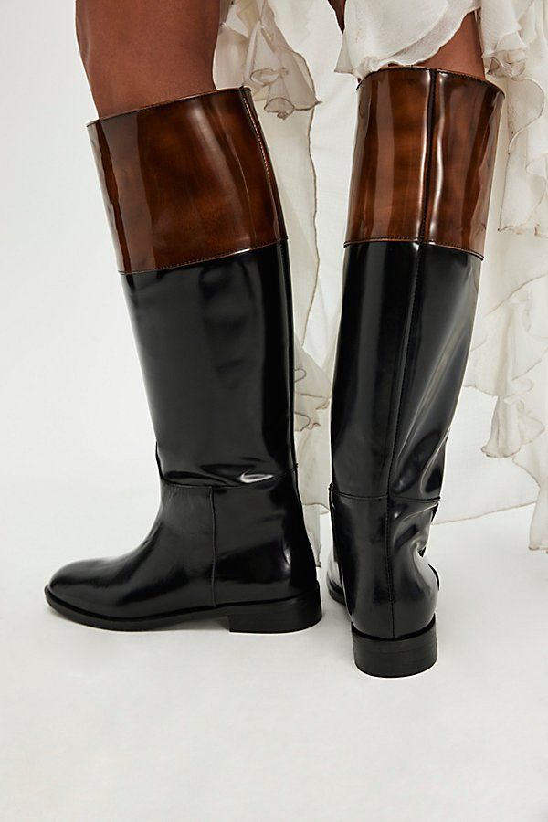 Contrasting tones and textures define these sleek riding boots, featured in a tailored style with glossy patent leather paneling on a polish leather base. **Fit:** Slim, tailored calf shape **Features:** Tall style, pull-on design, round toe, polished leather uppers, contrasting patent leather paneling, flat sole, low heel **Why We | Two-Tone Tailored Riding Boots by FP Collection at Free People in Black, Size: EU 42 Elegant Leather Sole Knee-high Boots For Riding, Patent Leather Knee-high Boots For Work, Tailored Style, Black Riding Boots, Low Heels, Riding Boots, Patent Leather, Black And Brown, Two Tone