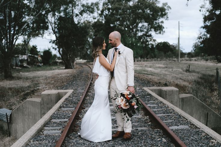 a bride and groom standing on train tracks