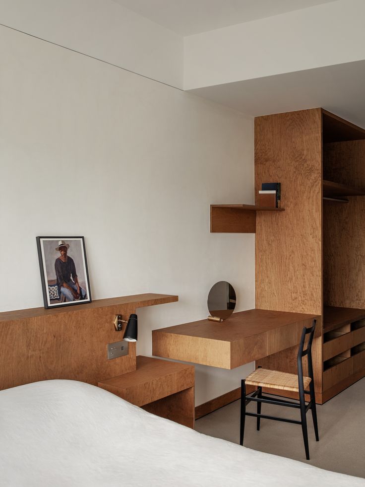 a bedroom with a bed, desk and shelves in the corner on either side of the room