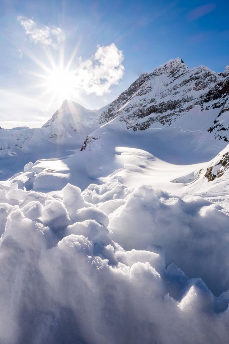 the sun shines brightly over snow covered mountains