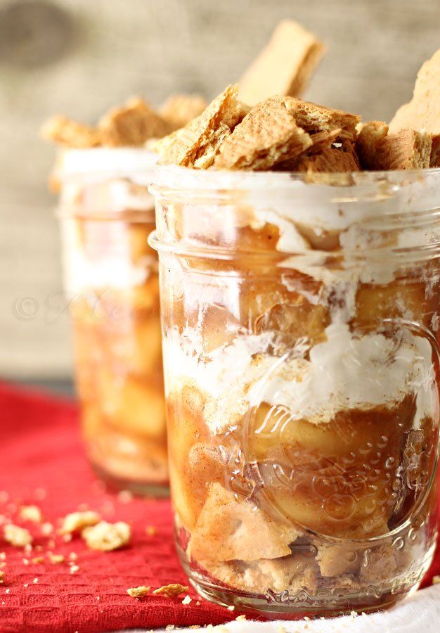 two jars filled with food sitting on top of a red table cloth next to a wooden spoon