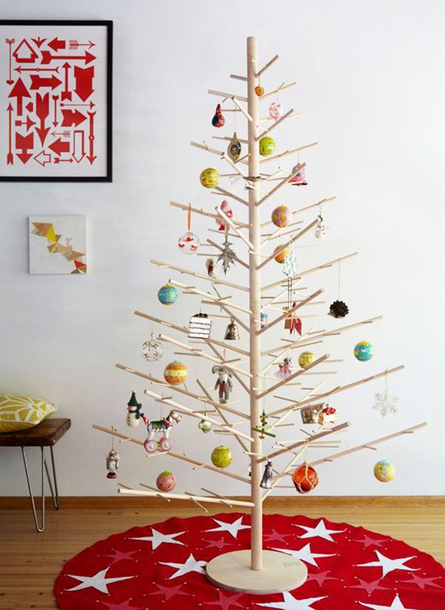 a christmas tree with ornaments on it in the corner of a living room next to a red round rug