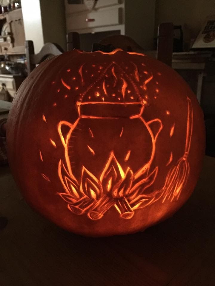 a pumpkin carved to look like a hogwart's crest with flames on it