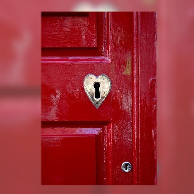 a red door with a heart shaped padlock on it's side and a keyhole in the middle