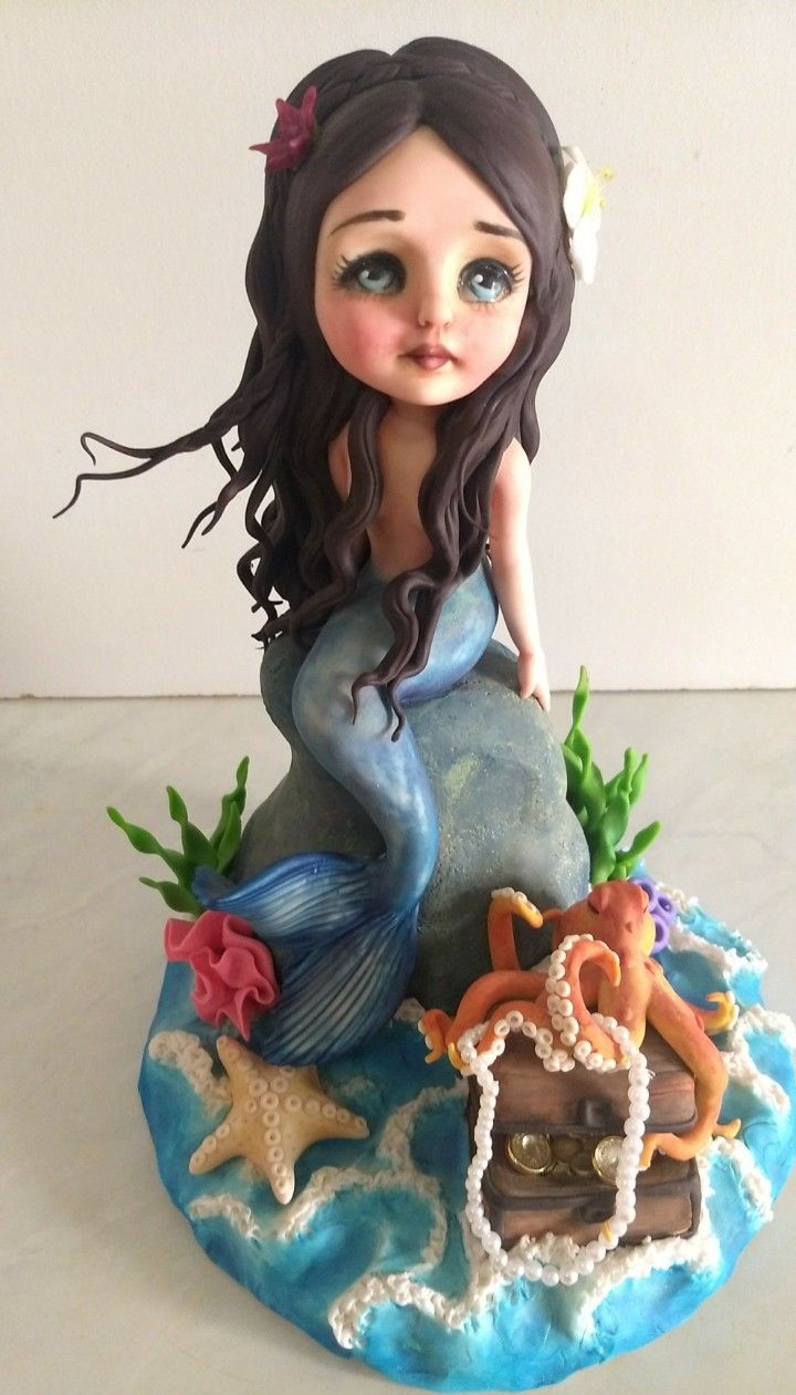 a little mermaid figurine sitting on top of a rock