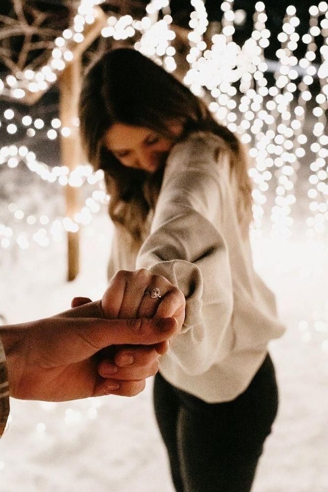 two people holding hands with lights in the background