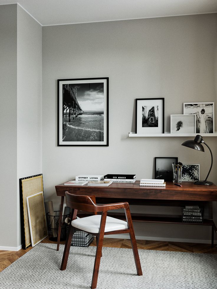 a room with a desk, chair and pictures on the wall above it in black and white