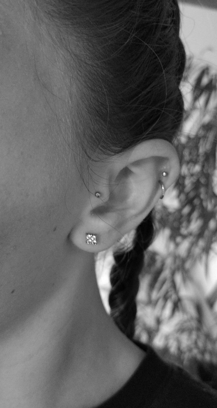 black and white photograph of woman with ear piercings looking at tree in the background