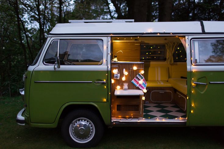 an old vw bus with its doors open and lights on the inside is lit up