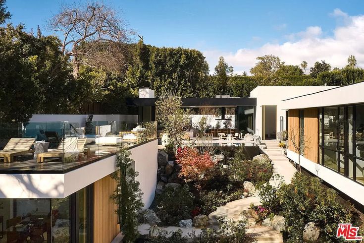 an aerial view of a modern house with trees in the foreground and patio area