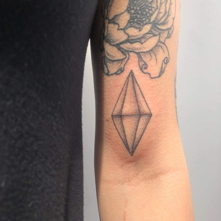 a woman's arm with a flower and diamond tattoo on it