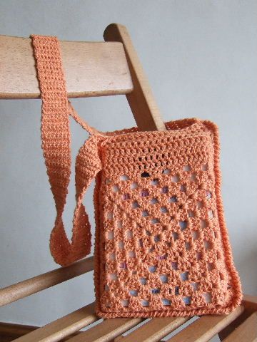 an orange crocheted purse sitting on top of a wooden chair