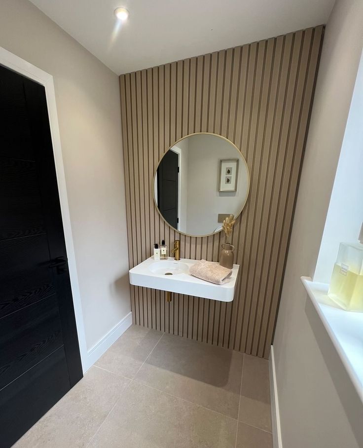 a white sink sitting under a round mirror next to a wall mounted faucet