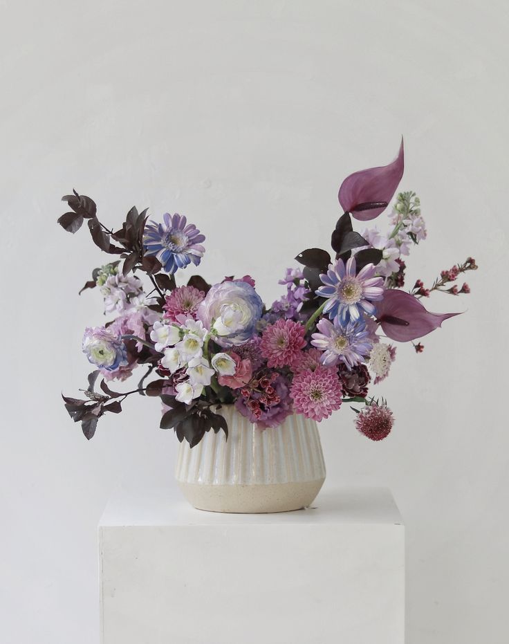 a white vase filled with purple and white flowers