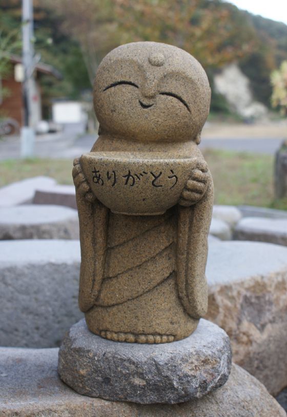 a small buddha statue sitting on top of a stone slab in front of some rocks