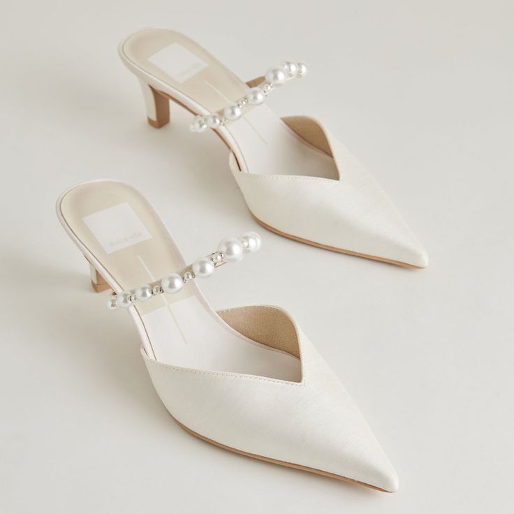 a pair of white shoes with pearls on the heel