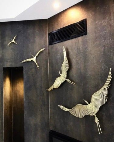 three metal birds are hanging on the wall