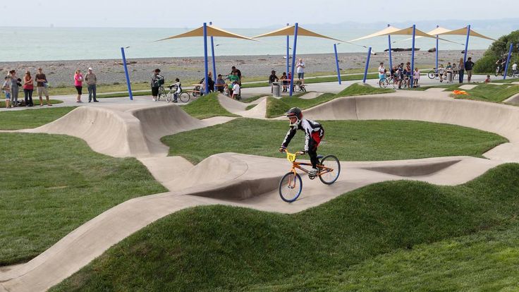 a man riding a bike through a park filled with ramps and grass covered in umbrellas