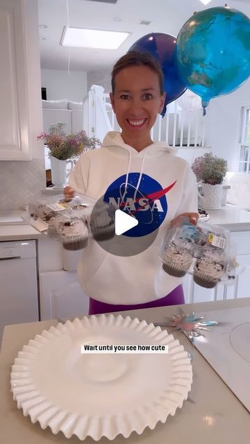 a woman is holding some cupcakes in her hands while standing next to a paper plate