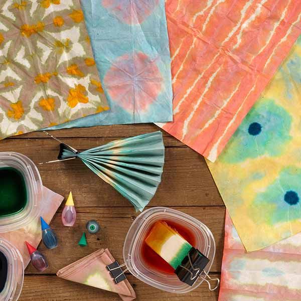 several craft supplies are laid out on a table with colorful dyes and paper umbrellas