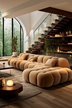 a living room filled with lots of furniture next to a stair case in front of a window