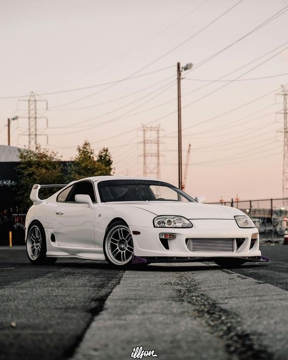 a white sports car parked on the street in front of power lines and telephone poles