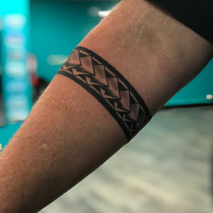 a man's arm with a tattoo on it and a clock in the background