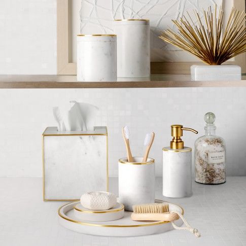 bathroom accessories displayed on shelves in white and gold