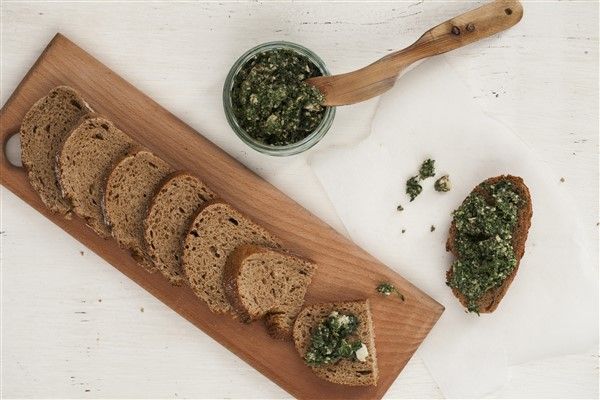 slices of bread with spinach spread on them next to a bowl of pesto