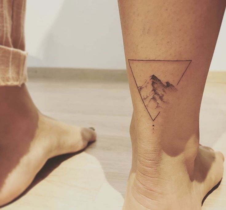 a person's foot with a mountain tattoo on the side of their left leg