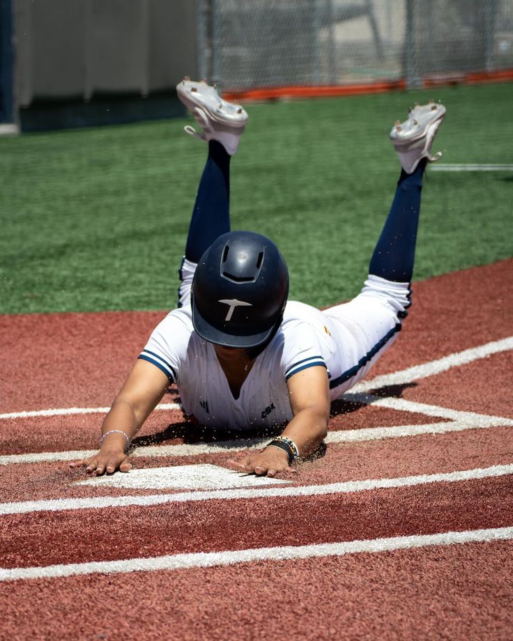 a baseball player laying on the ground with his feet up and hands in the air